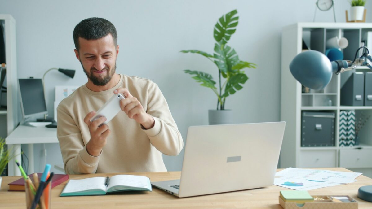 Man holding a credit card at a desk with laptop