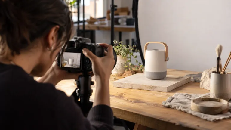 A founder photographing a tangible product prototype for a crowdfunding campaign in a small studio