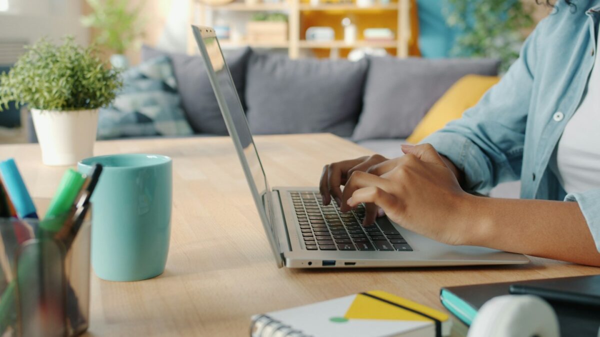 Person typing on a laptop at a wooden desk