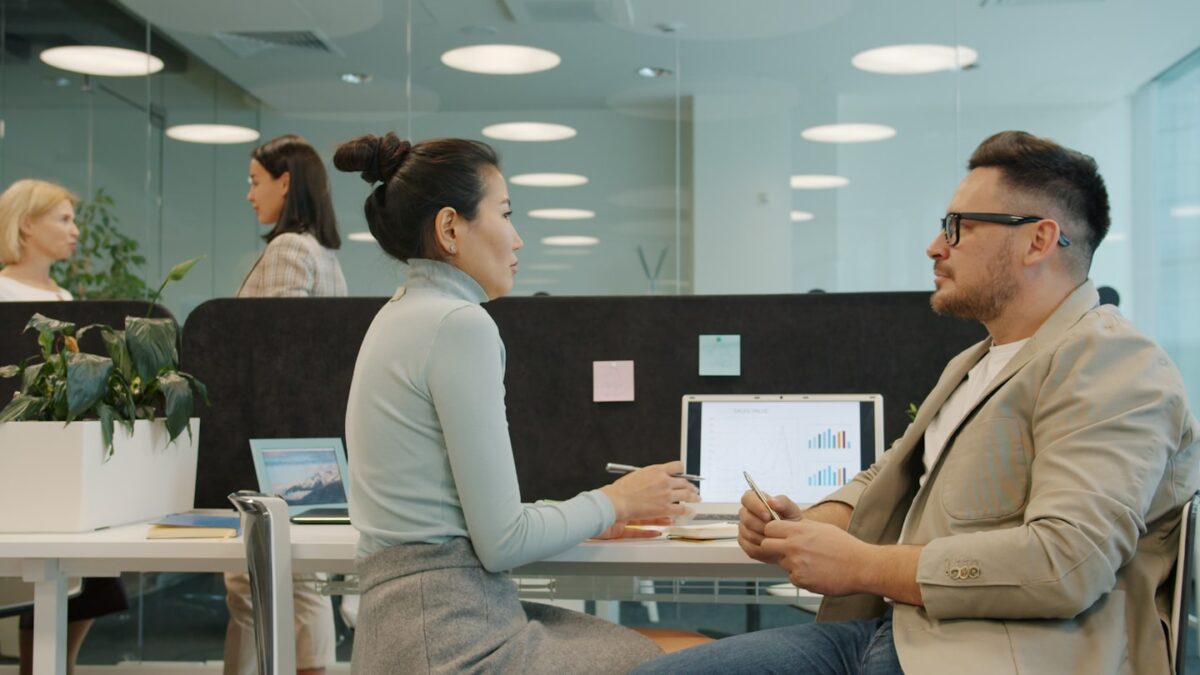 Two colleagues discussing work at their desks