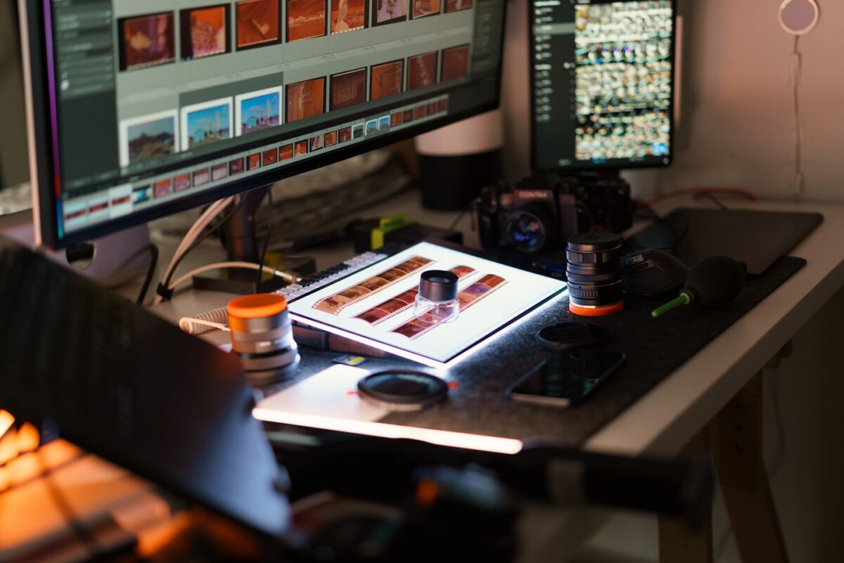 A desk with computer monitors and photography equipment