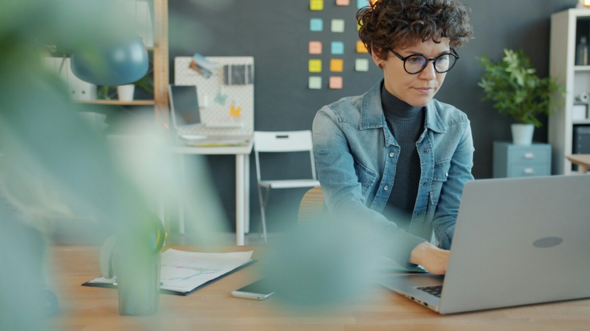 A woman with curly hair working on a laptop