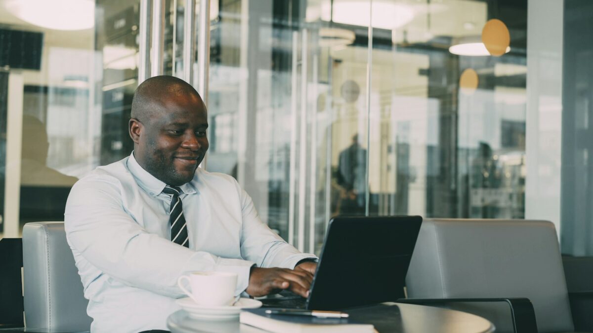Man laughing while working on laptop in cafe
