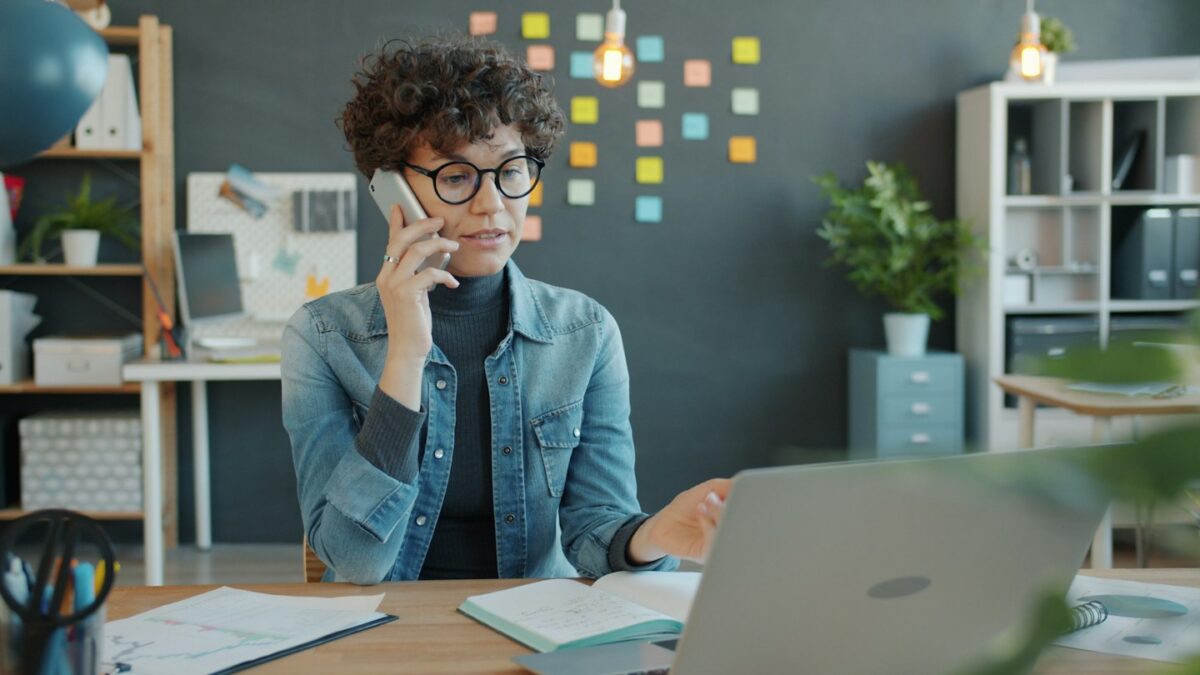 Woman talking on phone at desk with laptop