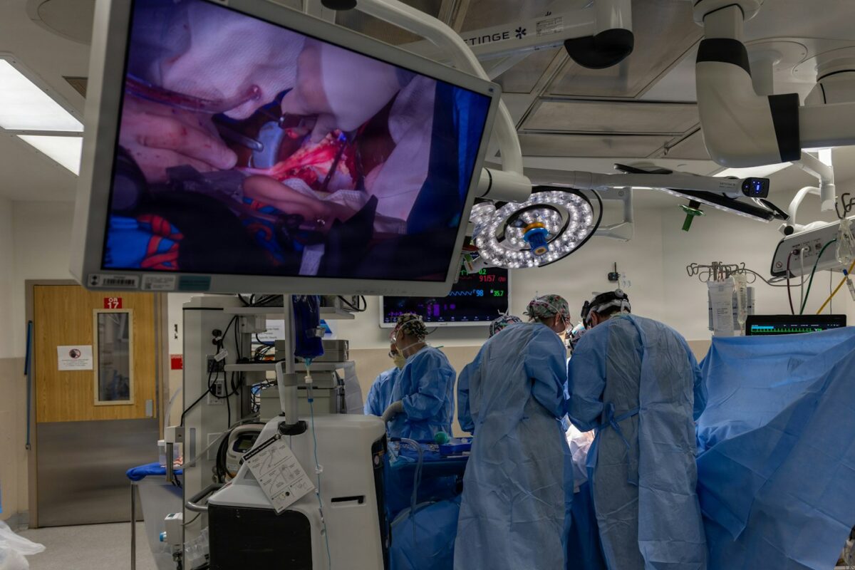 Surgeons operate while viewing the procedure on a large screen