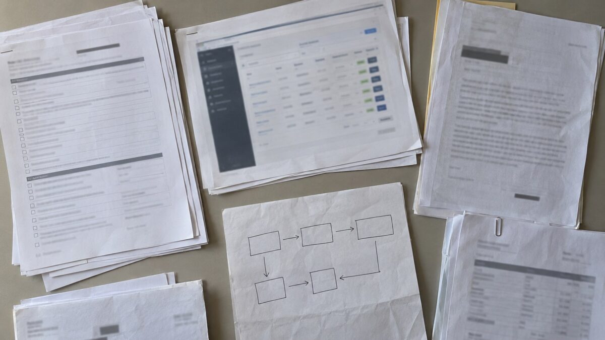 Overhead view of anonymized questionnaires, approval papers, a blurred subscription management screen printout, and a hand-drawn funds-flow sketch.