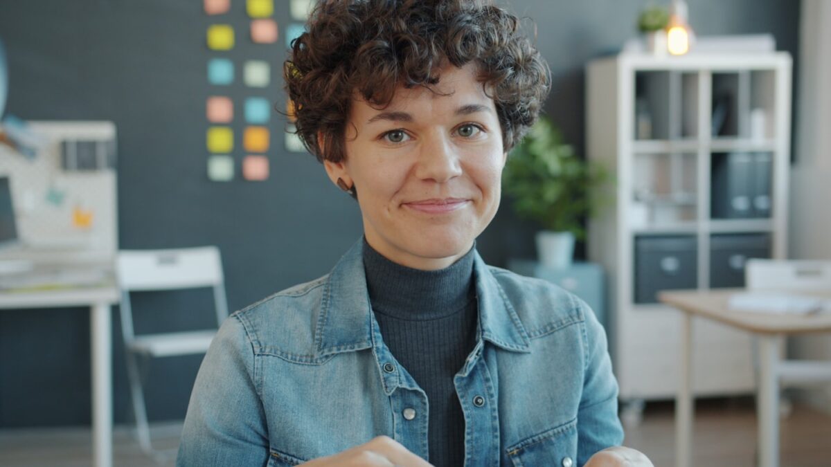 A woman with curly hair smiles in an office