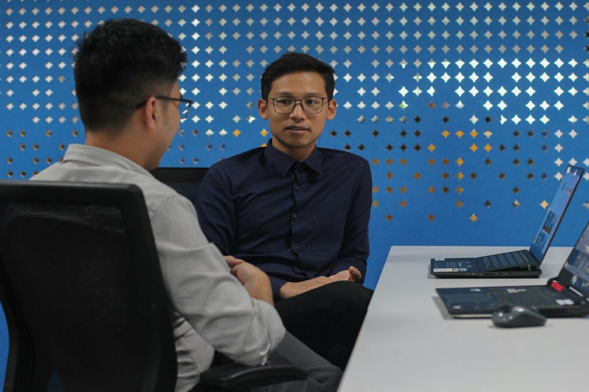 two men sitting at a table talking to each other