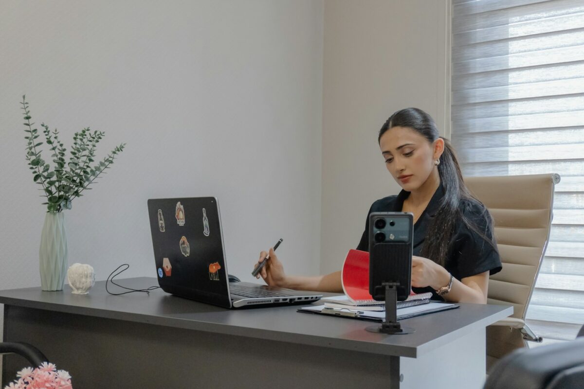 Woman working at a desk with laptop and phone